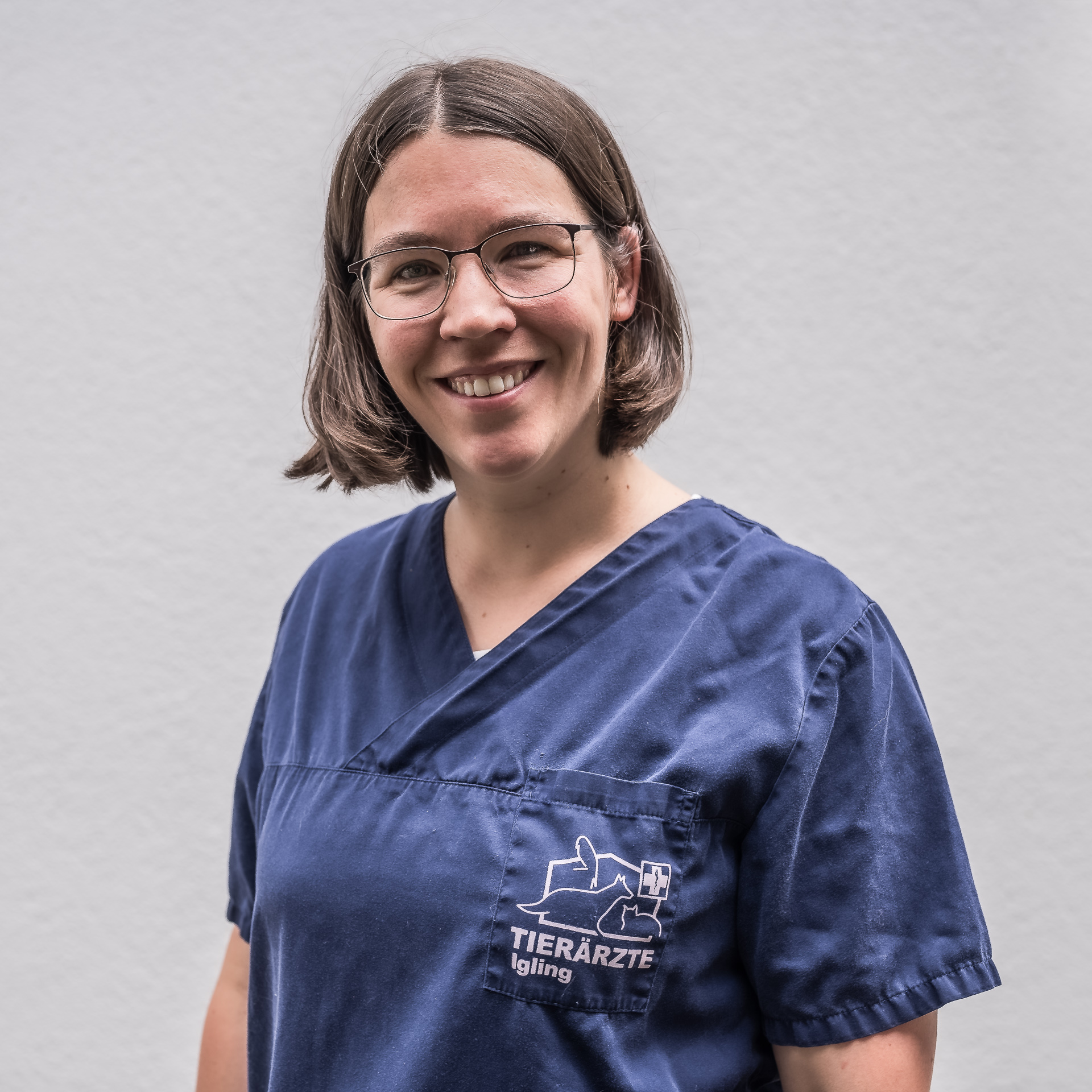 Tierärztin Dr. Simone Gaier steht vor hellem Hintergrund und schaut nett lächelnd in die Kamera.