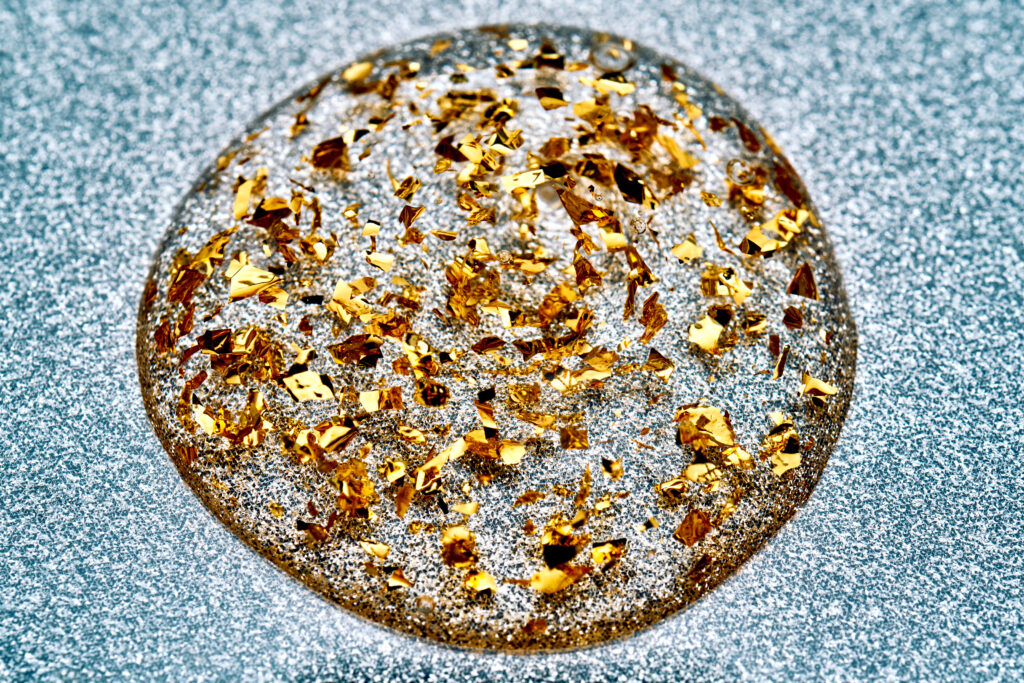 macro-shot-of-clear-liquid-droplet-with-gold-flake